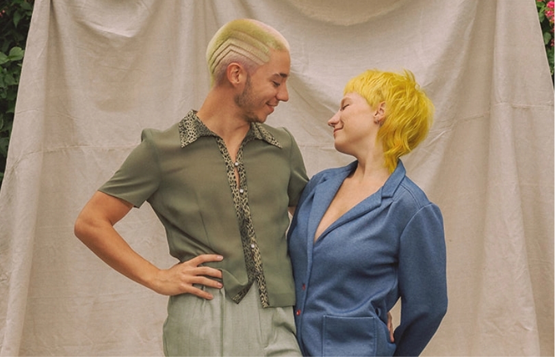 A young man and woman with multi-colored hair with modern, experimental styling. This salon experiments with non-traditional hair styles.