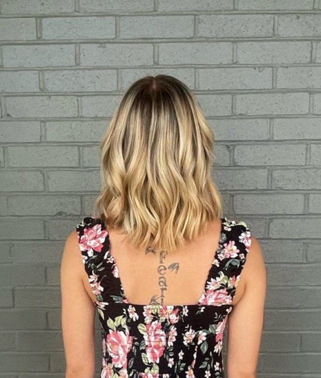 A woman with wavy blonde hair. This salon has experts in blonding services.