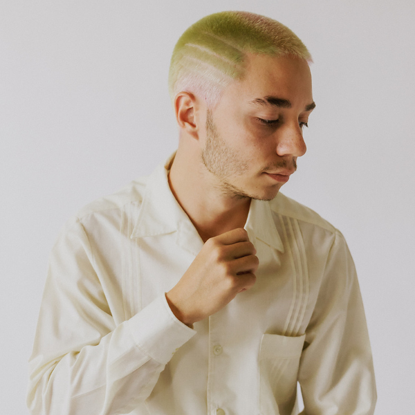A young man with multi-colored hair shaved short with lines shaved into the hair. This salon experiments with very unique cuts and styles for all genders.